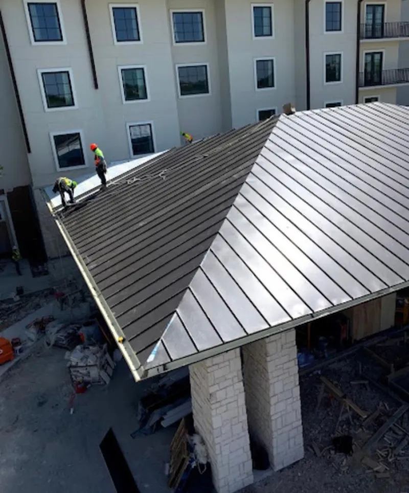 Crew installing standing seam metal roof panels on a commercial project in Gloversville
